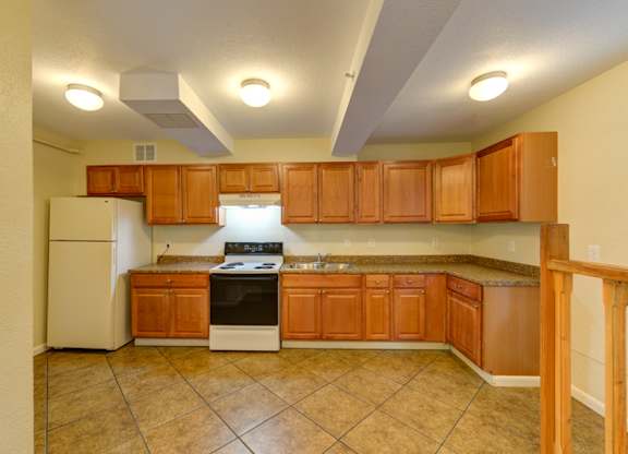 A kitchen with brown cabinets and a white refrigerator.