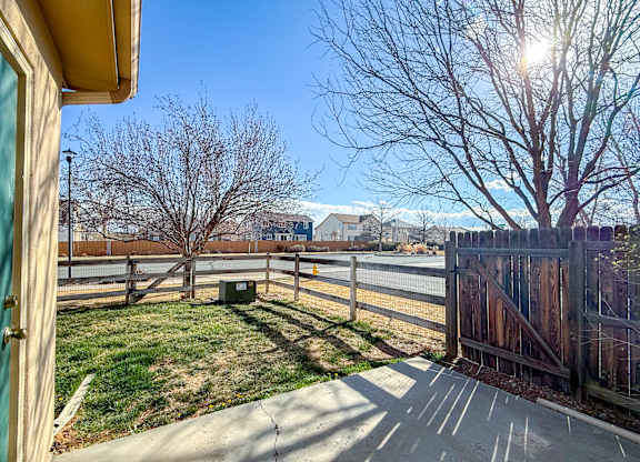 A view from a window of a backyard with a fence and a tree.