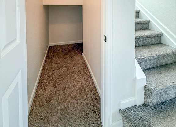 A hallway with a staircase and a light on the wall.