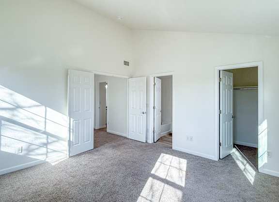 A sunny room with white doors and carpeted floor.