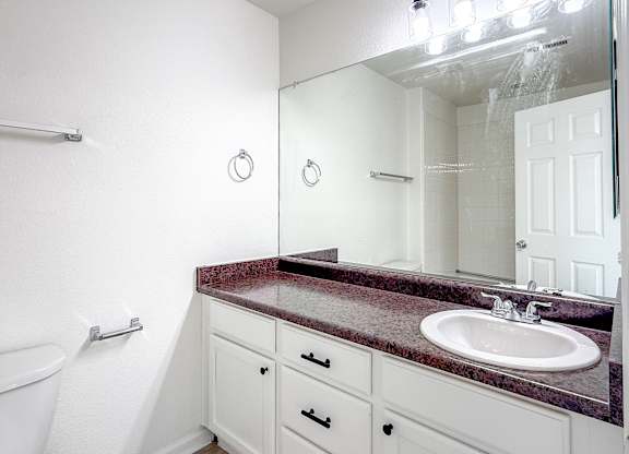 A bathroom with a marble countertop and white cabinets.