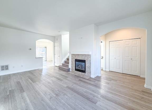 A spacious living room with a fireplace and hardwood floors.