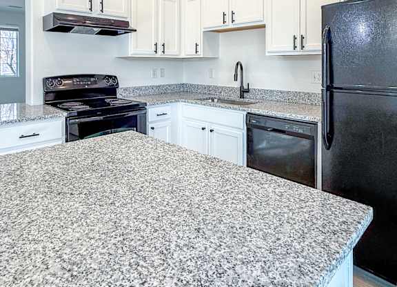 A kitchen with granite countertops and white cabinets.