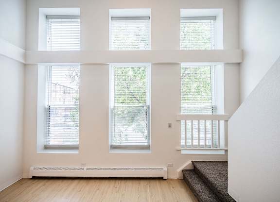 A room with three windows and a staircase.