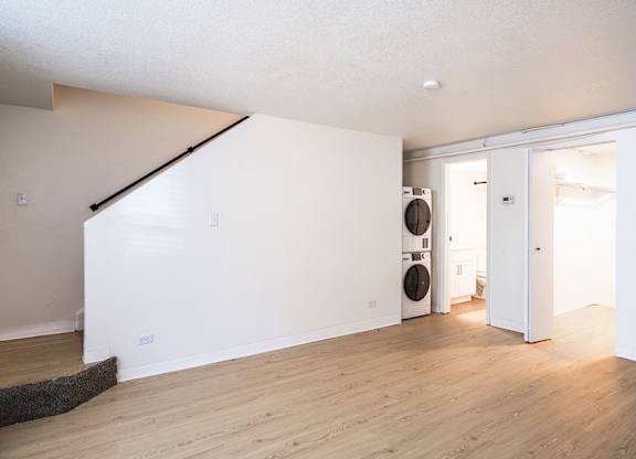 A room with a white wall and a door leading to another room.