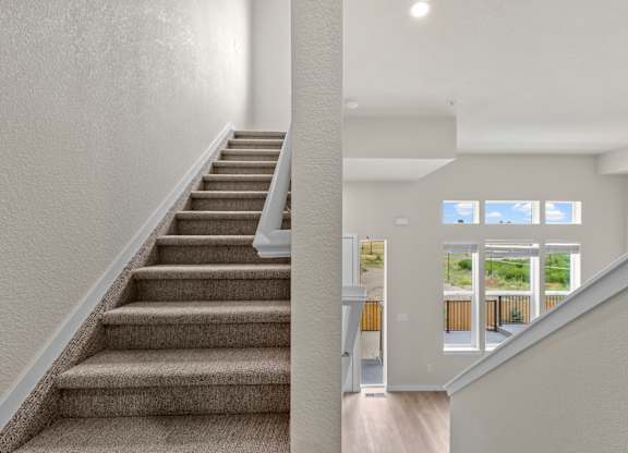 Staircase with a carpeted runner and a wooden handrail at The Townhomes at Pine Drive, Parker, CO, Colorado