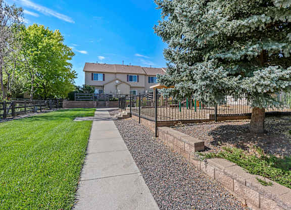 A house with a fence and a tree in front of it.