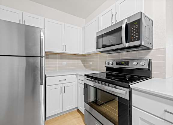 A kitchen with a refrigerator, microwave, oven and cabinets at Tallmadge Lofts in Denver, Colorado