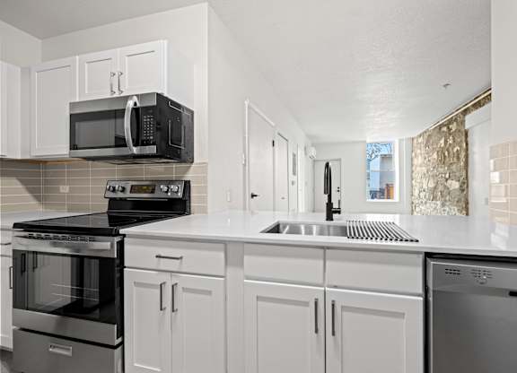 A kitchen with white cabinets and appliances at Tallmadge Lofts in Denver, Colorado