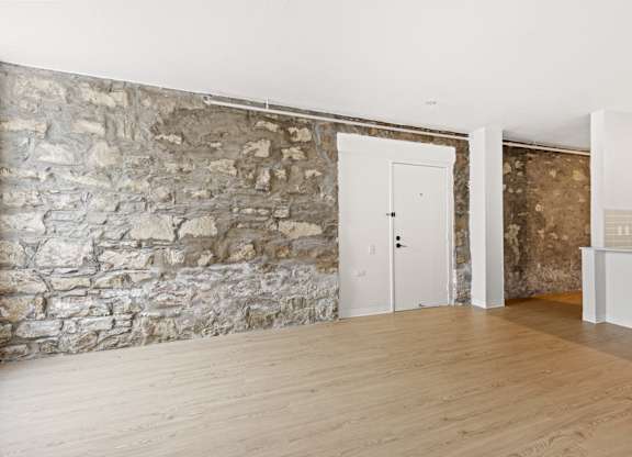 A room with a stone wall and wooden flooring at Tallmadge Lofts in Denver, CO
