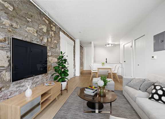 A living room with a stone wall and a flat screen TV at Tallmadge Lofts in Denver, CO