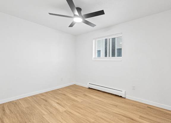 A room with a ceiling fan and a window with blinds.