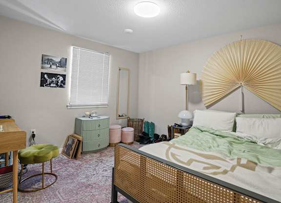 A bedroom with a bed, chair, and lamp.