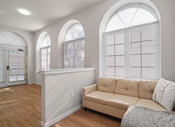 A living room with a tan couch and a large window.