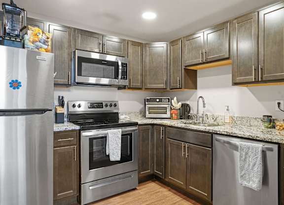 A kitchen with a stove, oven, refrigerator, and microwave.