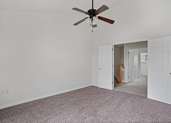 A room with a ceiling fan and carpeted floor.