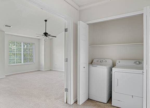 A room with a ceiling fan and two washing machines.