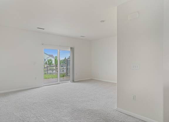A white room with a sliding glass door leading to a patio.