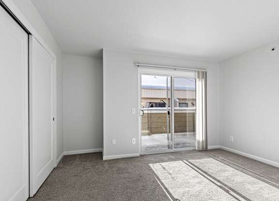 A room with a carpeted floor and a sliding glass door leading outside.