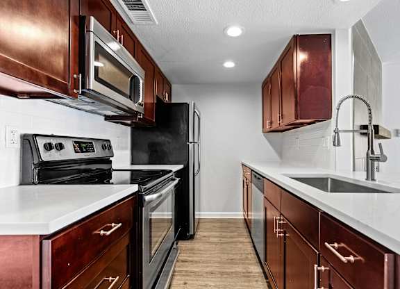 A kitchen with dark wood cabinets and white countertops.