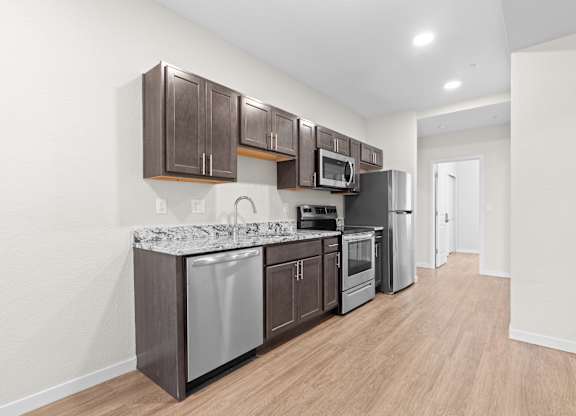 A kitchen with brown cabinets and a granite counter top.