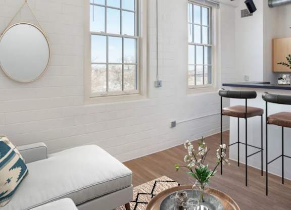 A living room with a white couch and a coffee table with a vase of flowers on it.