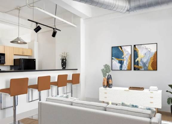 A modern living room with a grey sofa, a bar area with orange chairs, and two abstract paintings on the wall.