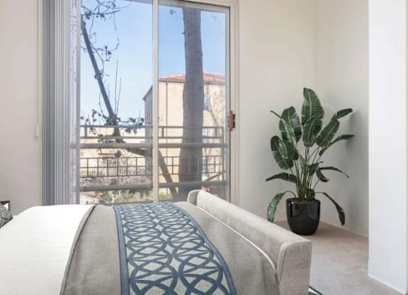 A bedroom with a bed, a couch, and a potted plant.