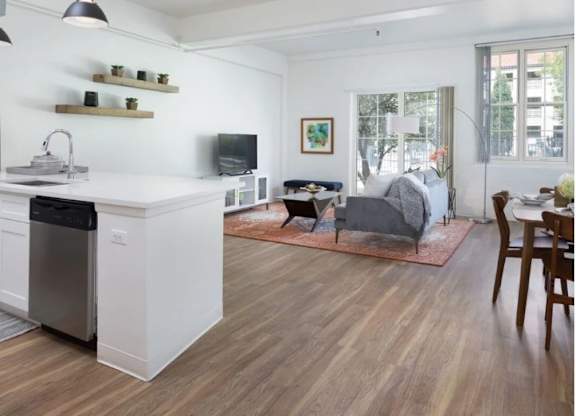 A modern kitchen with a white dishwasher and wooden floors.