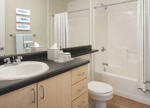 A white toilet sits in a bathroom next to a sink and a bathtub.