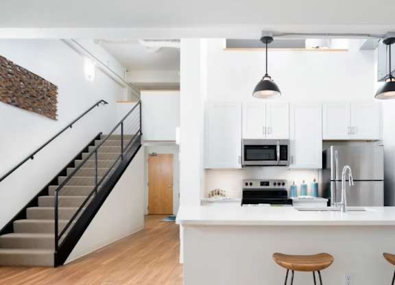 A kitchen with white cabinets and a bar area with stools.
