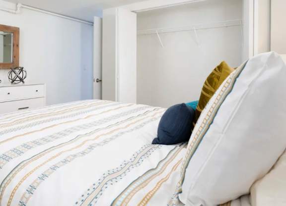 A bed with a white pillow and a striped comforter.