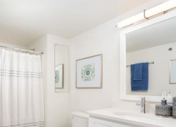 A white bathroom with a toilet, sink, and shower curtain.