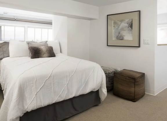A bedroom with a large bed and a framed picture on the wall.