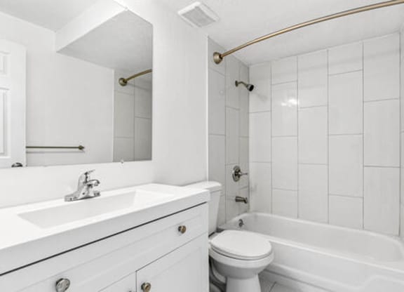 A white bathroom with a toilet, sink, and bathtub.