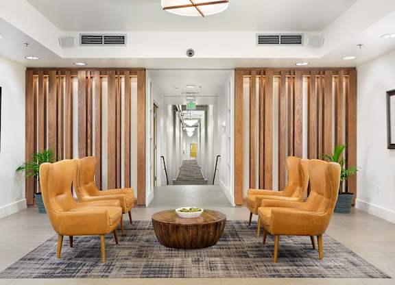 A hallway with a row of chairs and a coffee table.