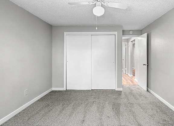 A room with a ceiling fan and a white door.