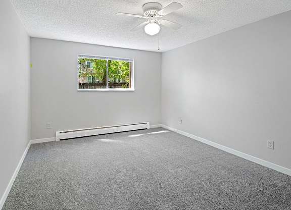 A room with a ceiling fan and a window.