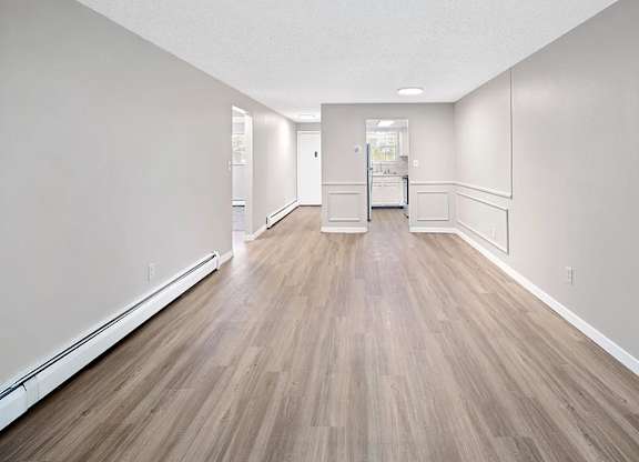 A long, empty hallway with wood flooring and white walls.