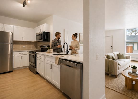 A man and woman are standing in a modern kitchen.