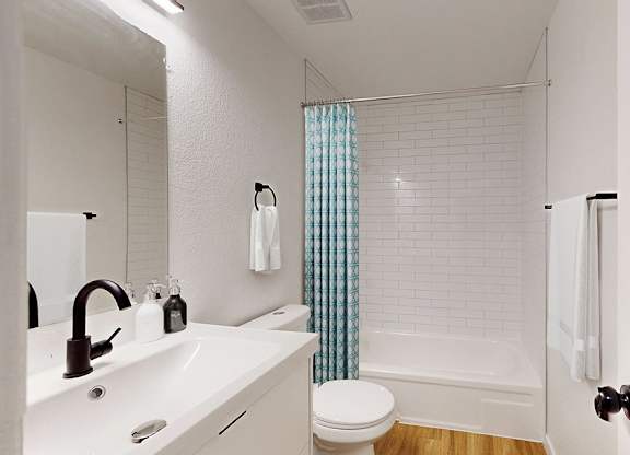 A white bathroom with a toilet, sink, and shower.