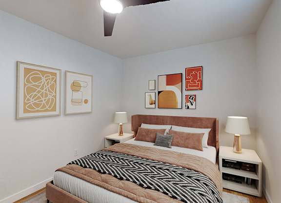 A bedroom with a bed, two lamps, and artwork on the wall.