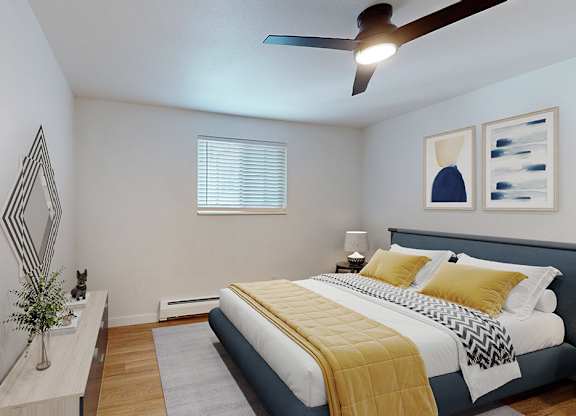 A bedroom with a bed, a plant, and a mirror.
