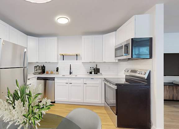 A modern kitchen with white cabinets and stainless steel appliances.