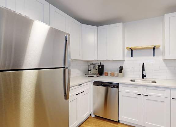 A kitchen with white cabinets and a stainless steel refrigerator.