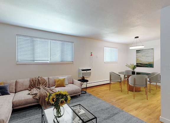 A living room with a grey couch, a glass coffee table, and a dining table with chairs.