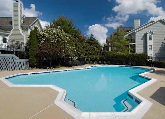 A large swimming pool surrounded by a white fence and trees.