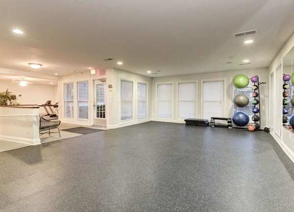 A spacious room with a grey floor and white walls, equipped with exercise balls and a bench.