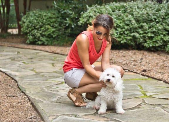 a woman is petting a white dog on the ground