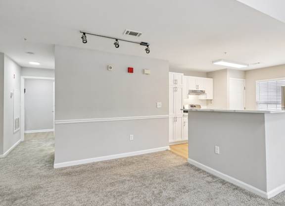 A spacious living room with a kitchen area in the background.